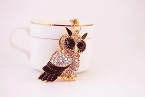 Detail of luxury owl keychain with crystal rhinestones next to a ceramic cup