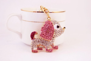 Dettaglio del portachiavi cane con strass rosa accanto a una tazza di ceramica bianca