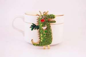 Nahaufnahme des grünen Strass-Drachen-Schlüsselanhängers mit goldener Basis und Emaille
