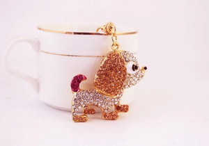 Dettaglio macro del portachiavi a cane dorato con strass colorati su tazza di porcellana