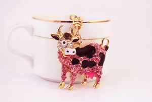 Dettaglio del portachiavi a mucca con strass rosa e smalto, appeso a una tazza di caffè