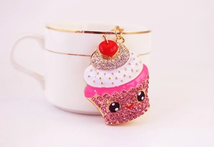 Détail d'un porte-clés cupcake mignon avec des strass roses et une chaîne dorée