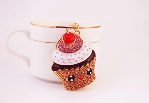 Détail d'un porte-clés cupcake avec strass roses et cerise rouge sur une tasse en céramique