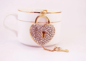 Détail du porte-clés cadenas cœur et clé orné de strass brillants avec finition dorée
