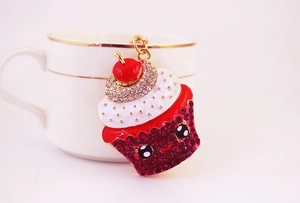 Détail d'un porte-clés cupcake avec strass rouges accroché à une tasse en céramique