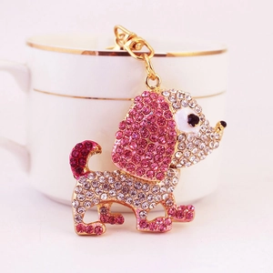Portachiavi a forma di cane dorato con strass rosa e bianchi appeso a una tazza bianca