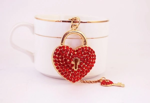 Détail du cadenas en cœur avec strass rouges et clé suspendu sur une tasse à café blanche