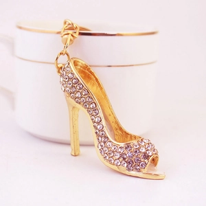 Elegante portachiavi a scarpa con tacco dorato e strass di cristallo scintillanti su bianco