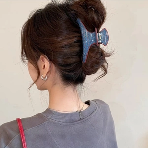 Detail view of denim texture hair claw clip with red polka dots in a messy bun hairstyle