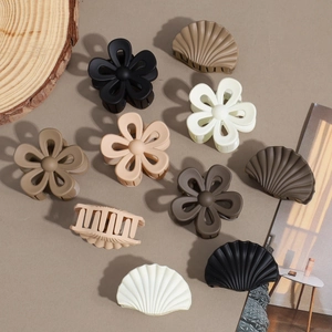 Matte star flower and shell claw clips set in earth tones on a minimalist background