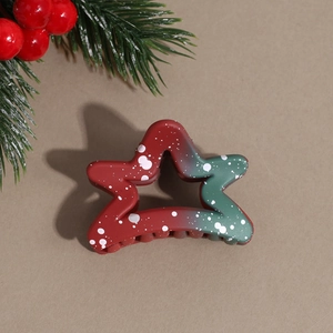 Detail of star-shaped Christmas hair claw with red and green gradient and snowflake pattern