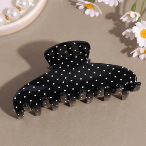 Dettaglio della grande molletta per capelli retrò francese nera con motivi a pois