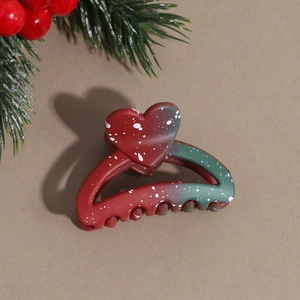 Detail view of heart-shaped hair claw with red-green gradient and festive paint dots