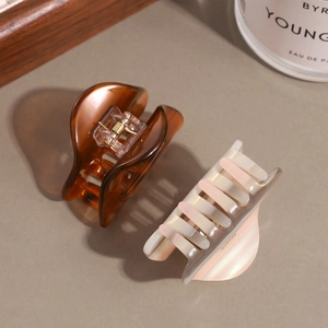 Retro hollow acetate hair claws in amber and pearlescent pink for elegant hairstyling