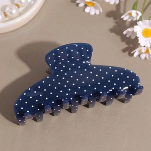 Dettaglio di una grande pinza per capelli blu scuro a pois con finitura in acetato