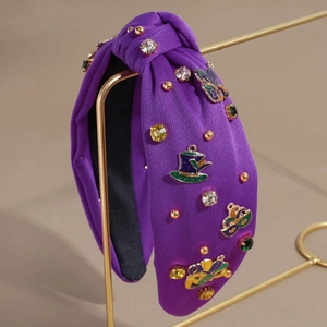 Détail du serre-tête de carnaval violet noué avec strass colorés et breloques festives en métal
