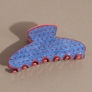Macro view of large denim-blue hair claw clip with classic red polka dots on brown base