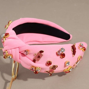 Cerchietto rosa annodato con cuori di strass e scritta LOVE dorata su supporto metallico