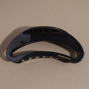 Close-up of black acetate moon hair claw with gold Creation France logo detailing