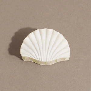 Detail view of the shell-shaped hair claw clip in matte cream finish with sturdy teeth