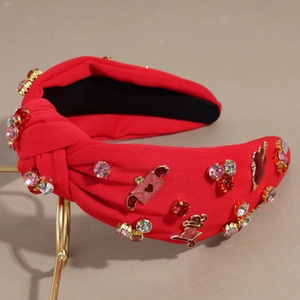 Dettaglio del cerchietto annodato rosso con strass multicolore e ciondoli Love dorati
