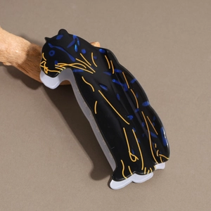 Détail de la pince à cheveux léopard noir avec des paillettes bleues sur bois