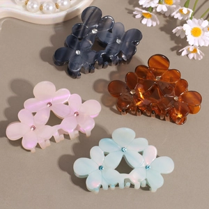 Floral acetate hair claws with rhinestones in four colors on a pearl display