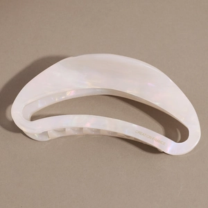 Detailed macro view of white acetate crescent hair claw with iridescent pearly luster