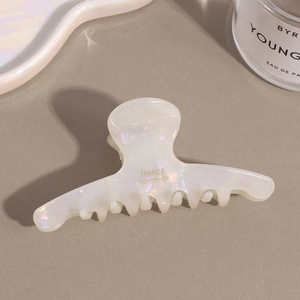 Detailed macro shot of white acetate shark clip with golden FRANCE handmade inscription