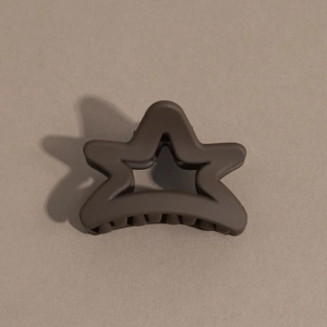 Detailed view of a dark brown star-shaped hair claw clip with a matte textured finish