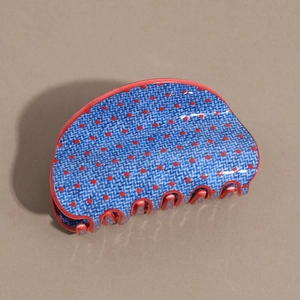 Detail of blue denim textured hair claw clip with red polka dots and glossy finish