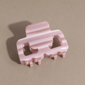 Dettaglio ravvicinato di una piccola molletta per capelli quadrata a righe rosa