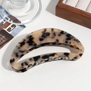 Close-up of a large tortoiseshell acetate crescent hair claw clip on a stone surface