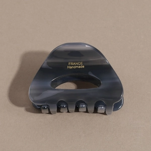 Detailed macro view of acetate hair claw clip with grey marble texture and gold lettering
