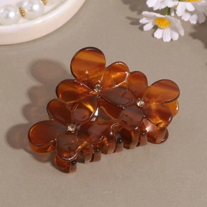 Detail of French floral cellulose acetate hair claw clip with rhinestones and amber texture