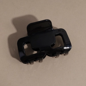 Dettaglio di un fermaglio per capelli quadrato nero lucido con design traforato elegante