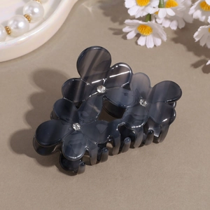 Close-up of a smoky gray floral hair claw clip featuring rhinestones and a resin finish