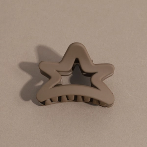 Detailed macro view of matte coffee brown star shaped hair claw clip on brown paper