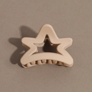 Macro shot of matte beige star-shaped hair claw clip with cutout design on textured background