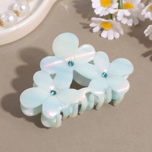 Detail of light blue floral acetate hair claw clip with rhinestones and pearlescent finish