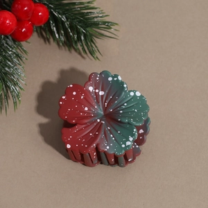 Detail view of flower hair claw clip with festive red and green gradient and snowflake dots
