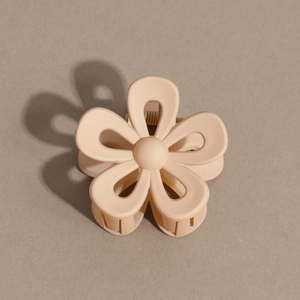 Detail view of a matte cream flower hair claw clip with a secure metal spring mechanism