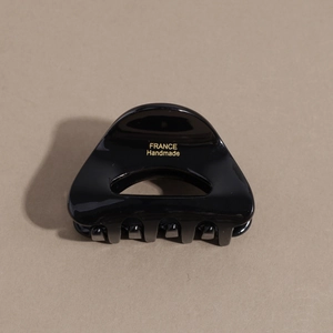 Detail of glossy black acetate hair claw clip featuring golden France Handmade lettering