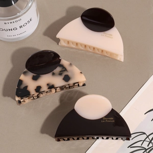 Three-piece acetate half-moon hair claw clips in cream, leopard print, and brown finishes