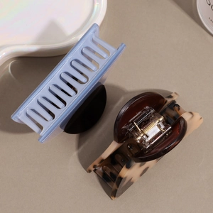 Minimalist light blue and tortoise shell hair claws for women displayed on a wavy tray