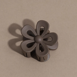 Macro view of a matte brown flower hair claw clip showing textured petals and teeth