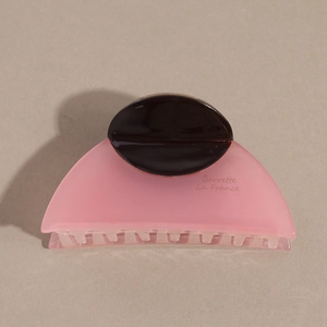 Close-up of semi-round pink acetate hair claw with brown inlay and elegant French text