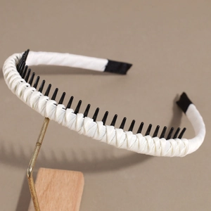 Detail of white satin headband featuring black non-slip comb teeth on interior
