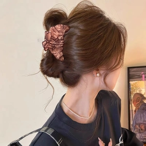 Brown tortoiseshell resin hair claw clip in bow shape worn on a woman's wavy hair