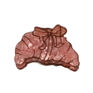 Pinkish-brown croissant-shaped hair claw with pearlescent texture and bow design